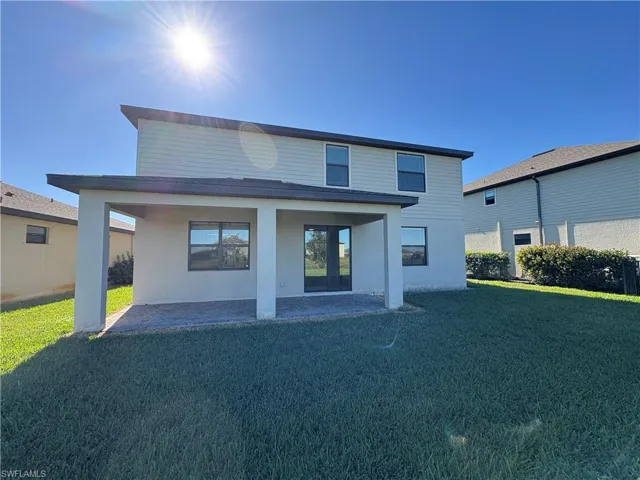 Rear view of property with a patio, a lawn, and stucco siding