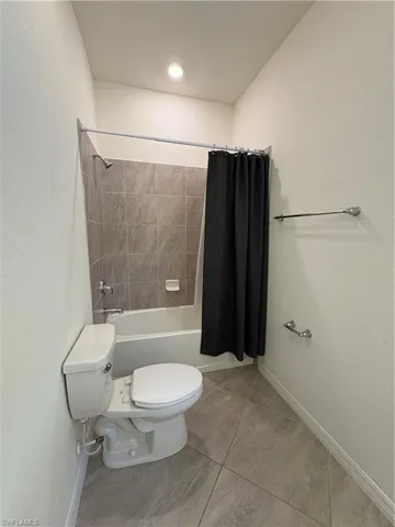 First Floor Bathroom featuring shower / bath combo, a textured wall, and light tile patterned floors