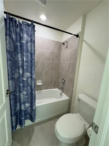 Full bathroom with shower / bath combo with shower curtain and tile patterned flooring