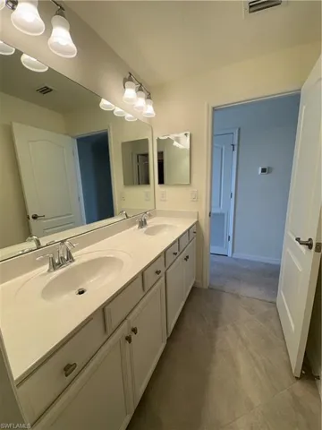 Full bathroom featuring double vanity and baseboards