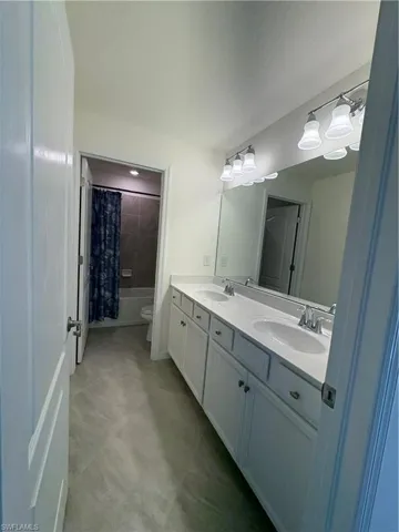 Bathroom featuring double vanity and shower / bath combo with shower curtain