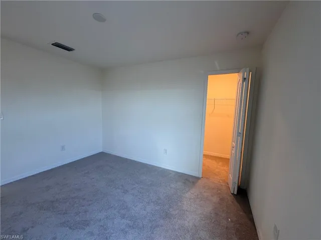 Spare room featuring dark carpet and baseboards