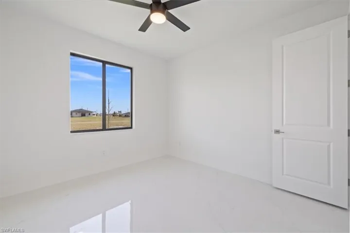 Unfurnished room featuring light marble finish flooring and ceiling fan