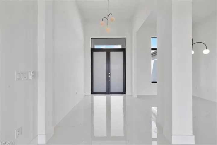 Entryway with a chandelier, light marble finish flooring, and french doors