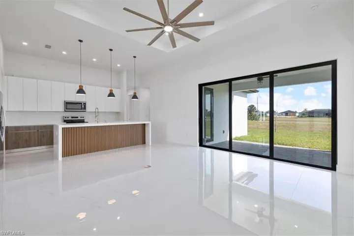 Kitchen featuring white cabinetry, modern cabinets, stainless steel microwave, a raised ceiling, and hanging light fixtures