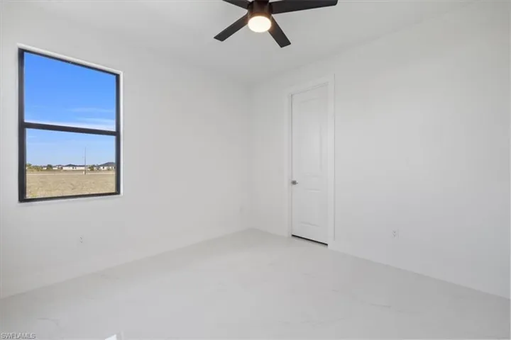 Spare room with light marble finish floors and a ceiling fan