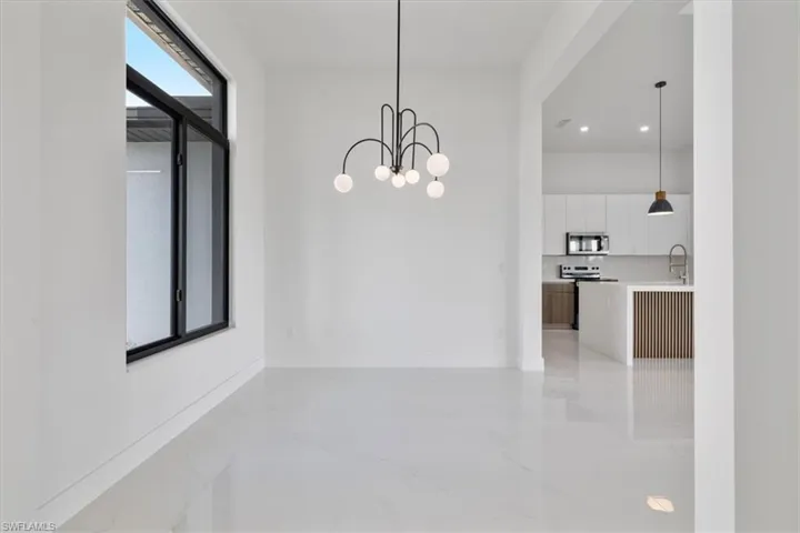 Unfurnished dining area with light marble finish floors and a chandelier