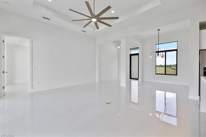 Empty room with a raised ceiling, a chandelier, recessed lighting, and a ceiling fan