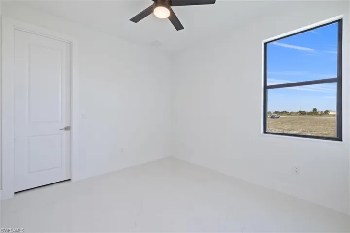 Spare room with marble look tiles and ceiling fan