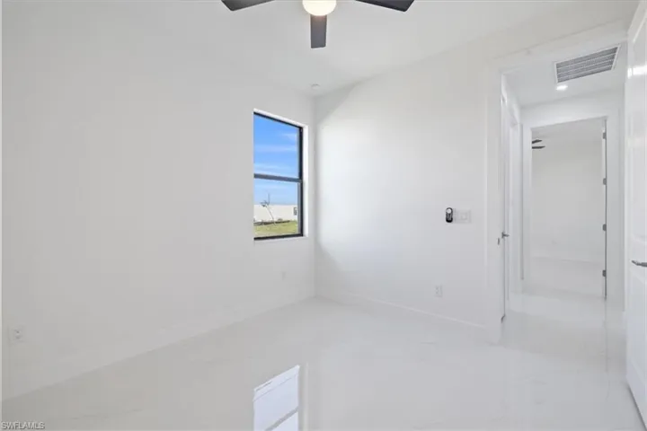 Unfurnished room featuring light marble finish flooring and a ceiling fan