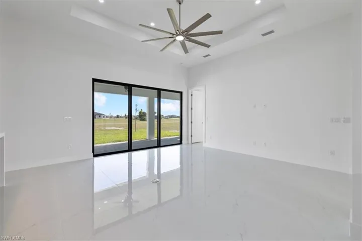 Empty room featuring a tray ceiling, recessed lighting, and a ceiling fan