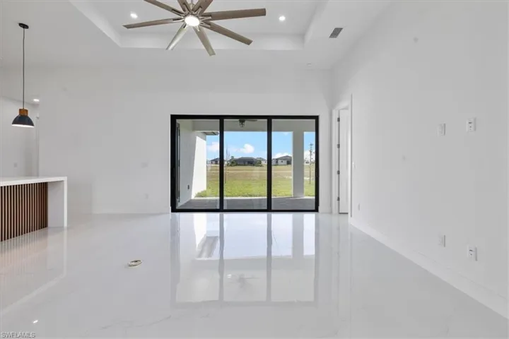 Empty room with light marble finish flooring, a tray ceiling, recessed lighting, and a ceiling fan