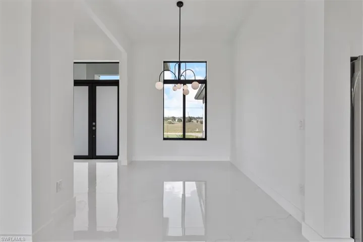Unfurnished dining area featuring marble tiled floors, a chandelier, and french doors
