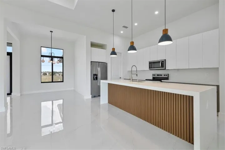 Kitchen with hanging light fixtures, stainless steel appliances, white cabinetry, a chandelier, and recessed lighting