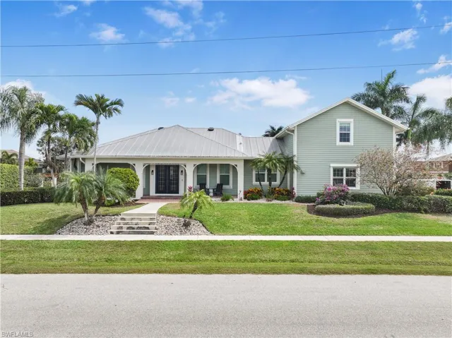 View of front facade featuring a front lawn, metal roof, and french doors