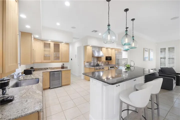 Kitchen featuring a sink, wine cooler, wall chimney range hood, light tile patterned flooring, and recessed lighting