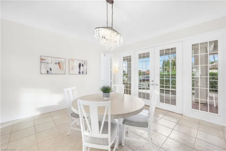 Dining area with tile patterned floors, a chandelier, crown molding, baseboards, and french doors