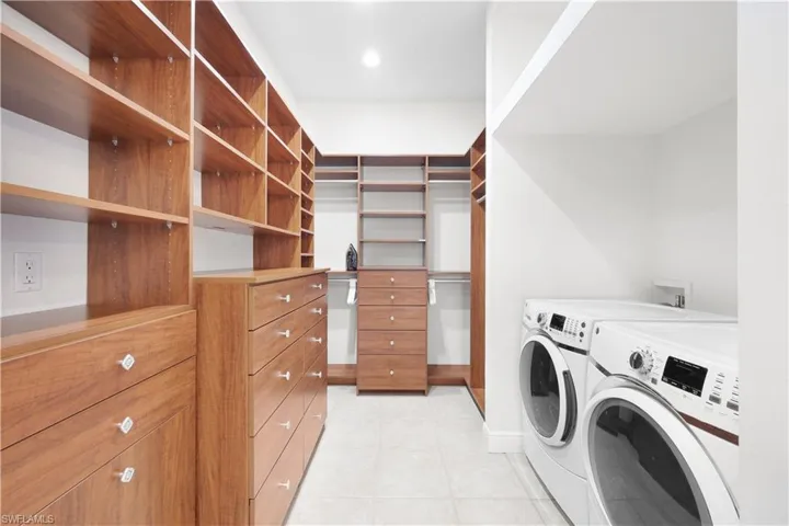 Laundry room with washer and clothes dryer and light tile patterned floors