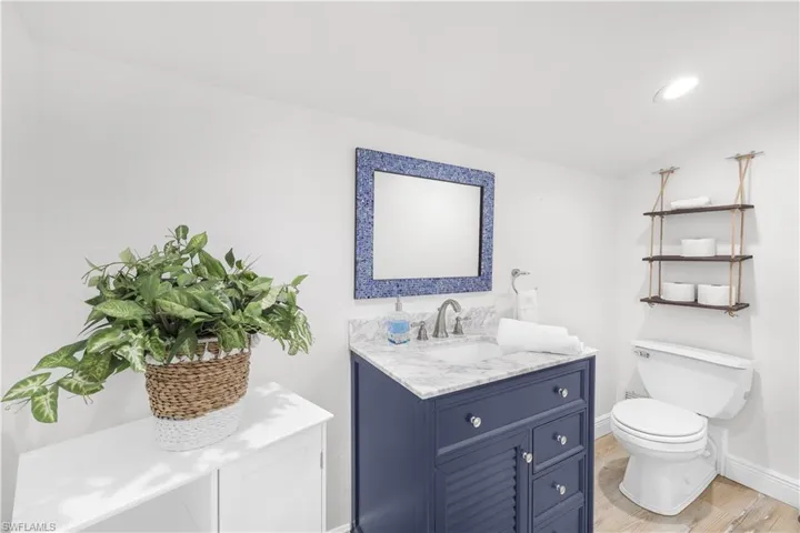 Bathroom with wood finished floors, toilet, baseboards, vanity, and recessed lighting
