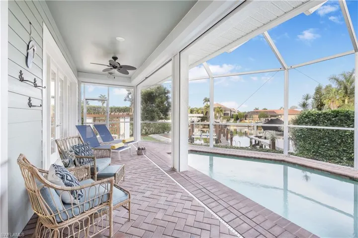 Sunroom / solarium with ceiling fan, a water view, and a pool