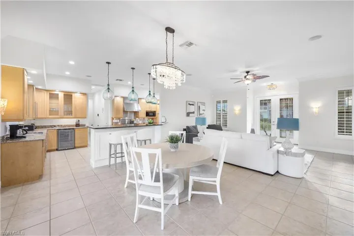 Dining space with wine cooler, light tile patterned floors, a ceiling fan, crown molding, and recessed lighting