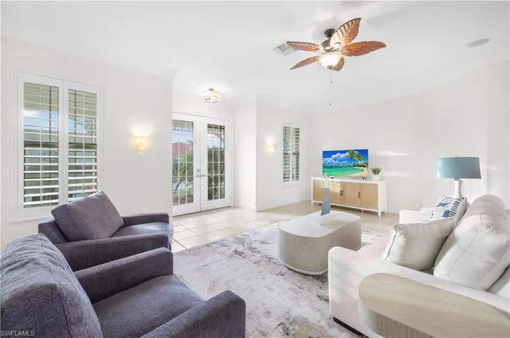 Living room with french doors, light tile patterned floors, baseboards, a ceiling fan, and crown molding