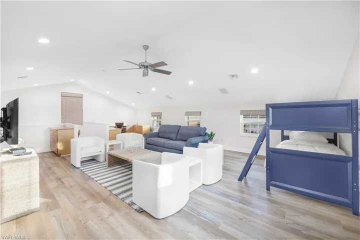 Living area featuring vaulted ceiling, ceiling fan, light wood finished floors, healthy amount of natural light, and recessed lighting
