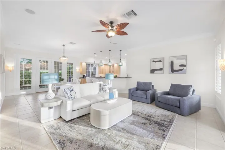 Living area with light tile patterned floors, plenty of natural light, a ceiling fan, baseboards, and ornamental molding