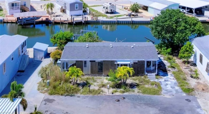 Waterfront property featuring a private boat dock, a detached storage shed, an exterior porch, and mature palm trees