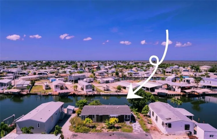 Waterfront property featuring direct canal access, a paved driveway, and mature landscaping