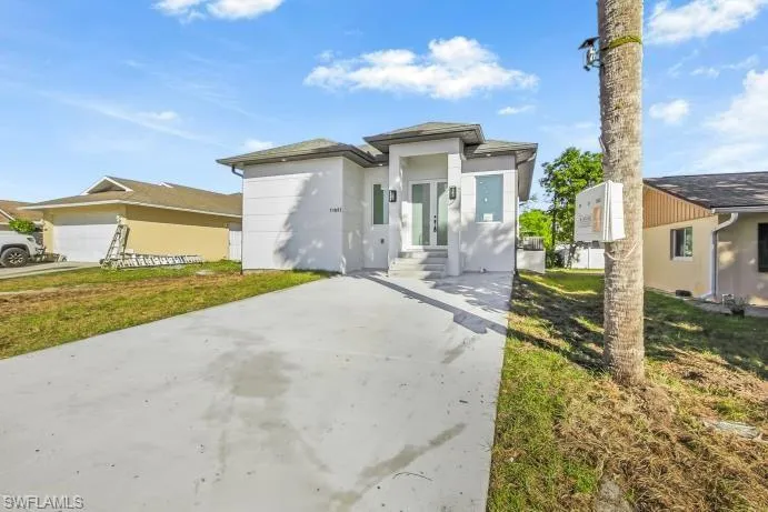 Prairie-style home with a front lawn, driveway, and stucco siding