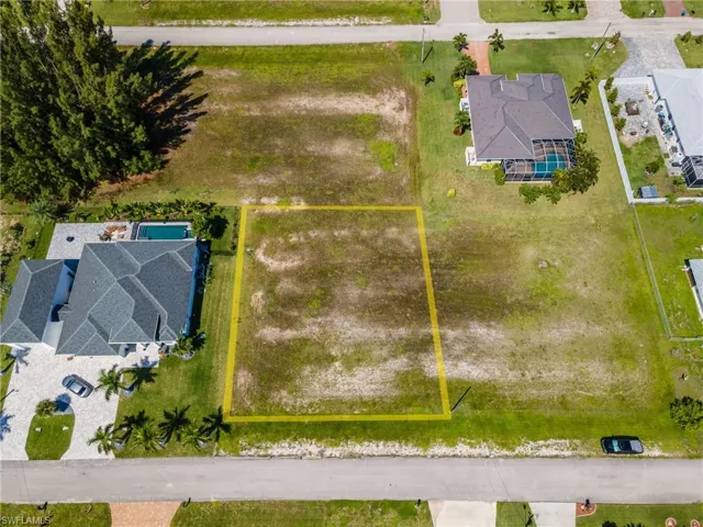 Vacant lot with surrounding residential properties, bordering a paved road