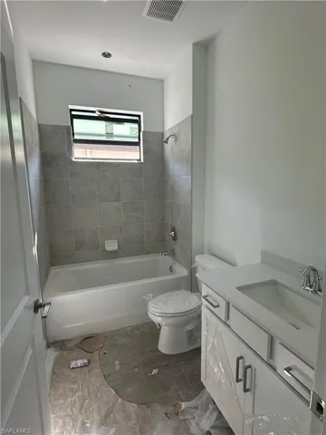 Full bathroom with vanity, tiled shower / bath combo, and tile floors