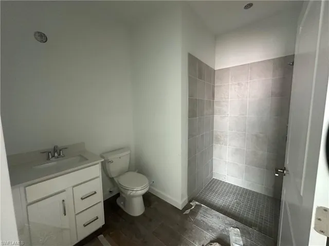 Bathroom with tiled shower, toilet, and vanity