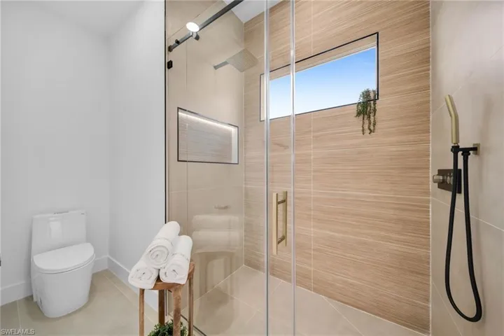 Full bathroom with tile patterned flooring, toilet, baseboards, and a stall shower
