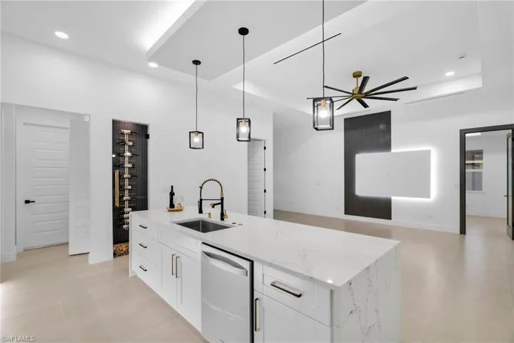 Kitchen with a sink, a tray ceiling, dishwasher, and open floor plan