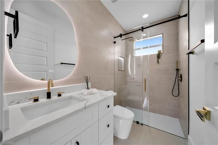 Full bath with vanity, tile patterned floors, toilet, and a stall shower