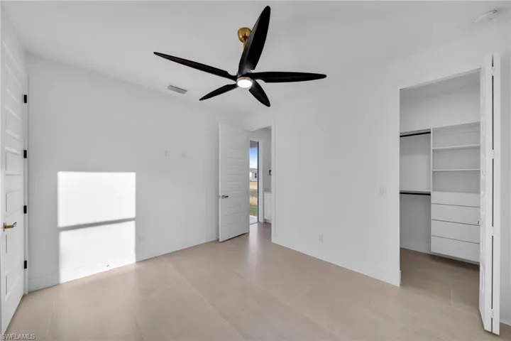 Unfurnished bedroom featuring visible vents, a ceiling fan, a closet, baseboards, and a spacious closet