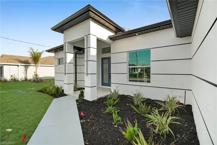 Property entrance featuring stucco siding, a lawn, and fence