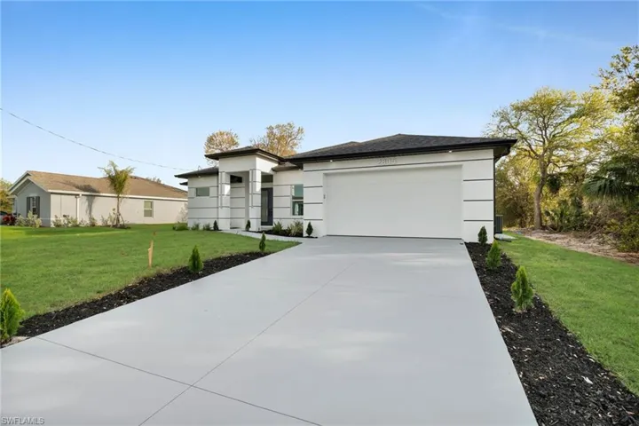 Prairie-style home featuring a garage, concrete driveway, a front yard, and stucco siding