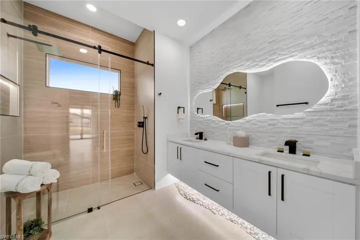 Bathroom featuring double vanity, tasteful backsplash, a stall shower, and a sink