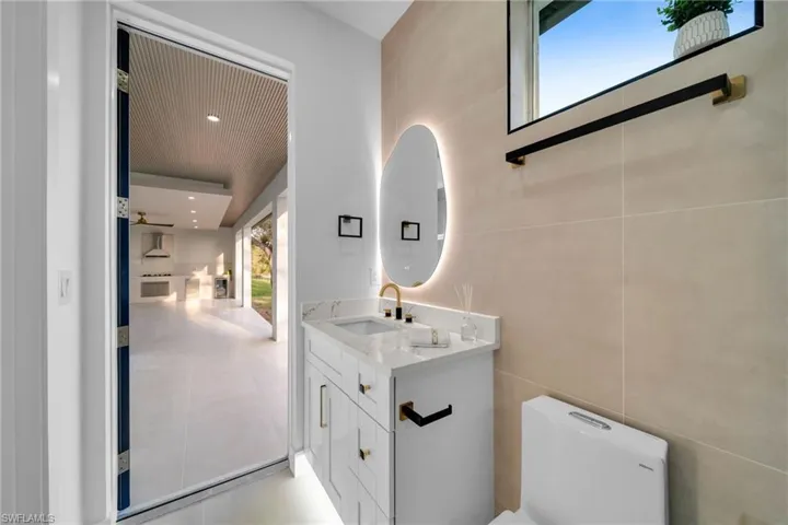 Half bathroom with vanity, tile walls, toilet, and tile patterned flooring