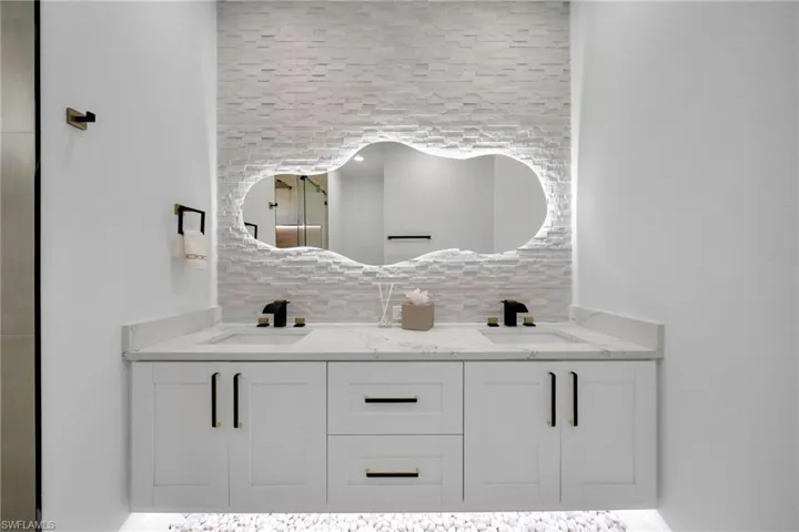 Full bathroom featuring double vanity, decorative backsplash, and a sink