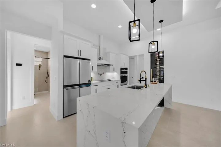 Kitchen featuring recessed lighting, a sink, a large island, white cabinets, and appliances with stainless steel finishes