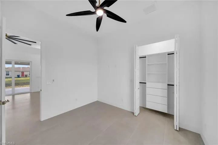 Unfurnished bedroom with ceiling fan, a closet, baseboards, and light tile patterned flooring
