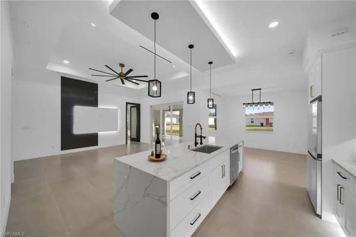 Kitchen with a sink, a raised ceiling, appliances with stainless steel finishes, and recessed lighting
