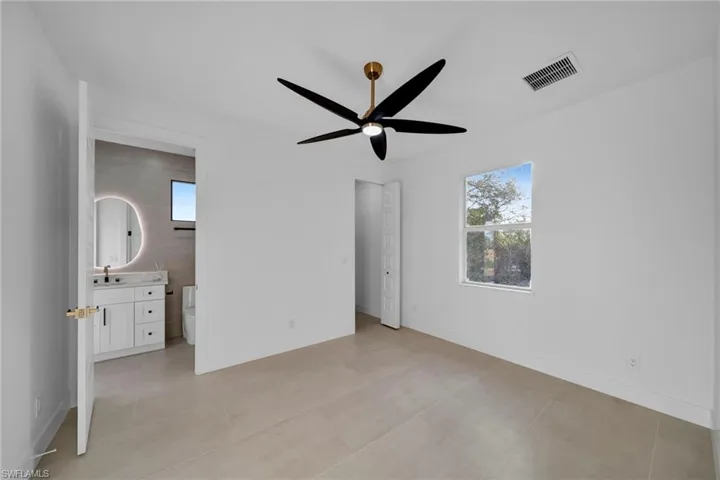 Unfurnished bedroom with visible vents, connected bathroom, baseboards, light tile patterned floors, and a sink