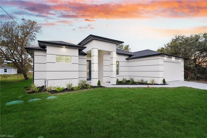 Prairie-style home featuring a front yard, an attached garage, concrete driveway, and stucco siding
