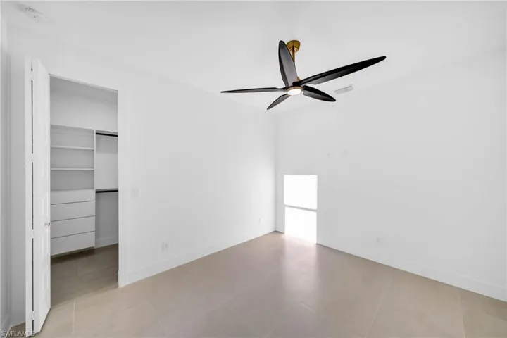 Unfurnished bedroom featuring visible vents, baseboards, a ceiling fan, and a spacious closet