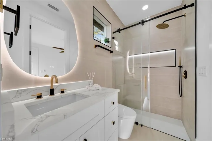 Bathroom featuring visible vents, a shower stall, toilet, and vanity